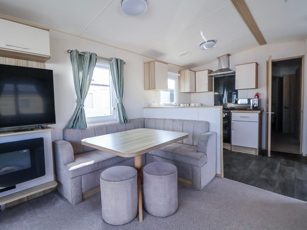A kitchen area with a table and chairs at St Michaels Caravan Park - 236 Towyn