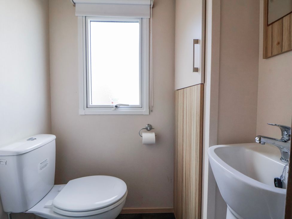 A bathroom with a toilet and sink at St Michaels Caravan Park - 236 Towyn
