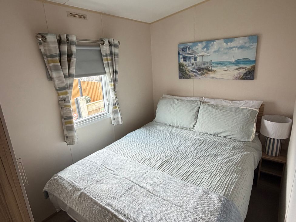 A bedroom with a bed and window at The Beachside Hideout - St Michaels Caravan Park Towyn