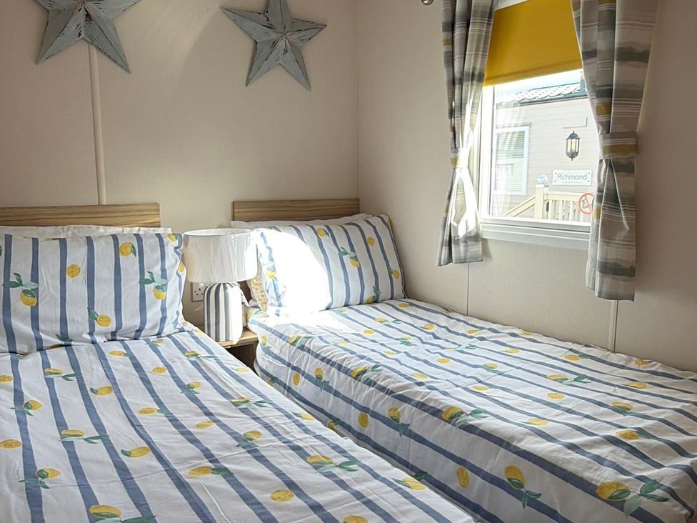 A bedroom with two beds and a window at The Beachside Hideout - St Michaels Caravan Park Towyn