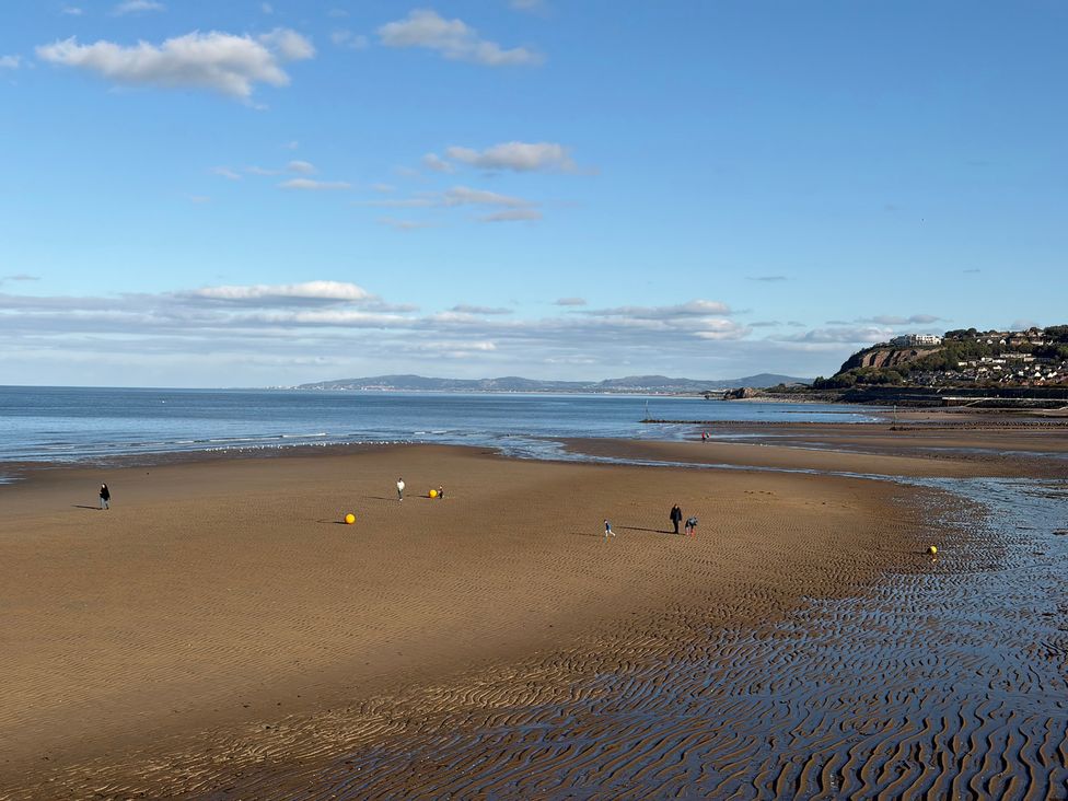 A beach with people walking near water at The Beachside Hideout - St Michaels Caravan Park Towyn