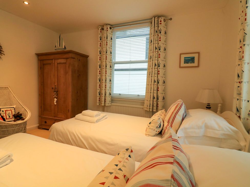 A bedroom with two beds and a wardrobe at Smugglers Cove Dartmouth