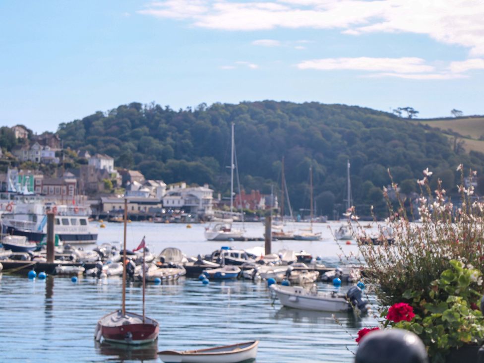 A view of boats on the water with buildings and trees in the background at Smugglers Cove in Dartmouth