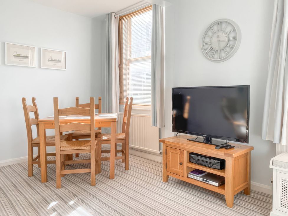 A dining room with a table and chairs with a television at Snugglers Cove in Dartmouth