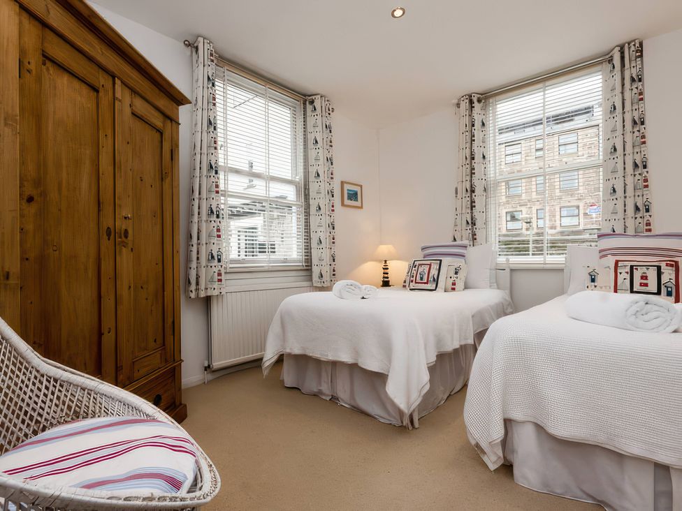 A bedroom with two beds and a wardrobe at Snugglers Cove in Dartmouth