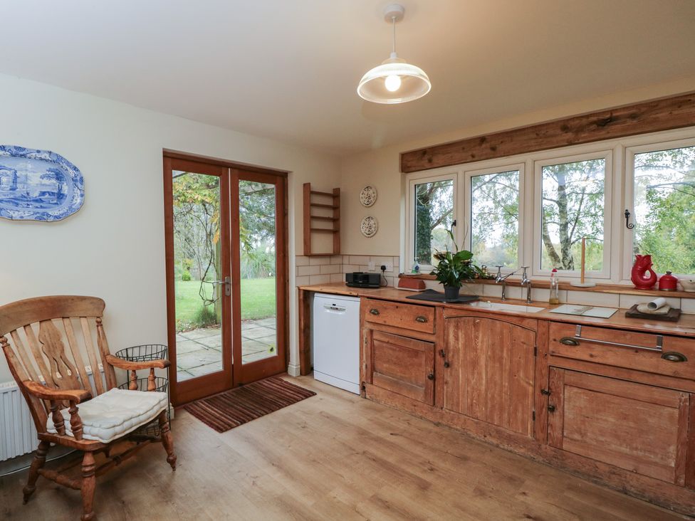 A kitchen with wooden cabinets and a rocking chair at Gardeners Hill Annex
