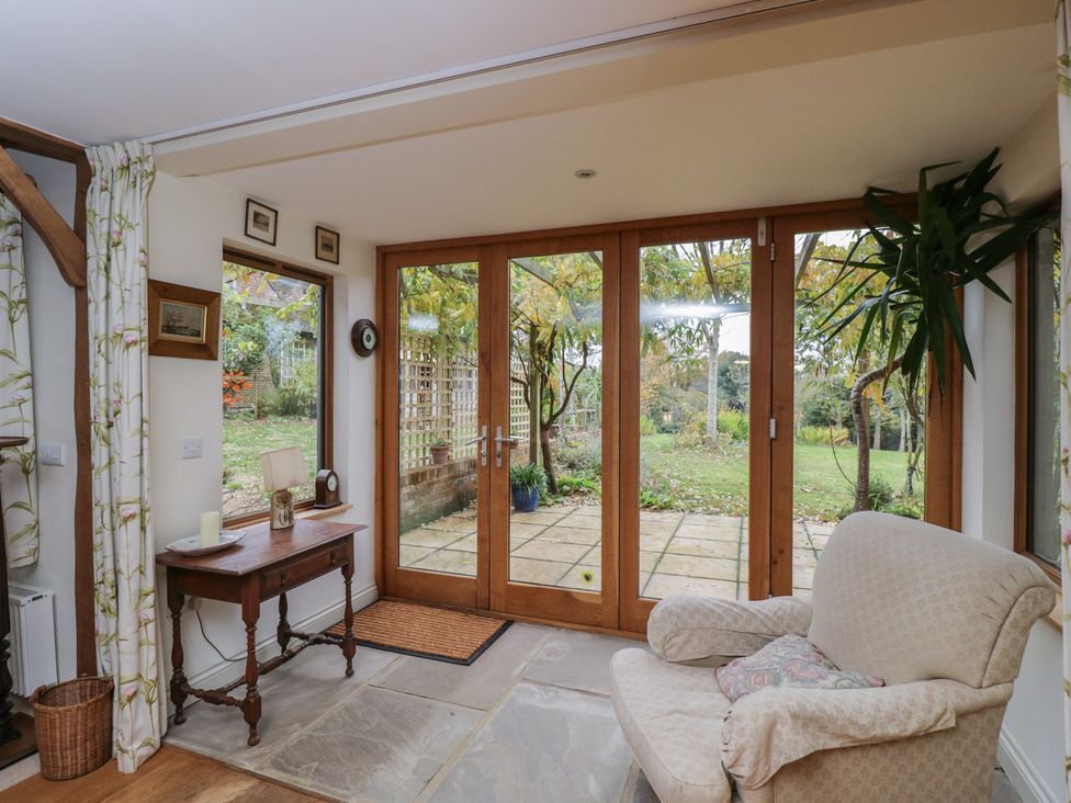 A sunroom with a table and chair overlooking a garden at Gardeners Hill Annex