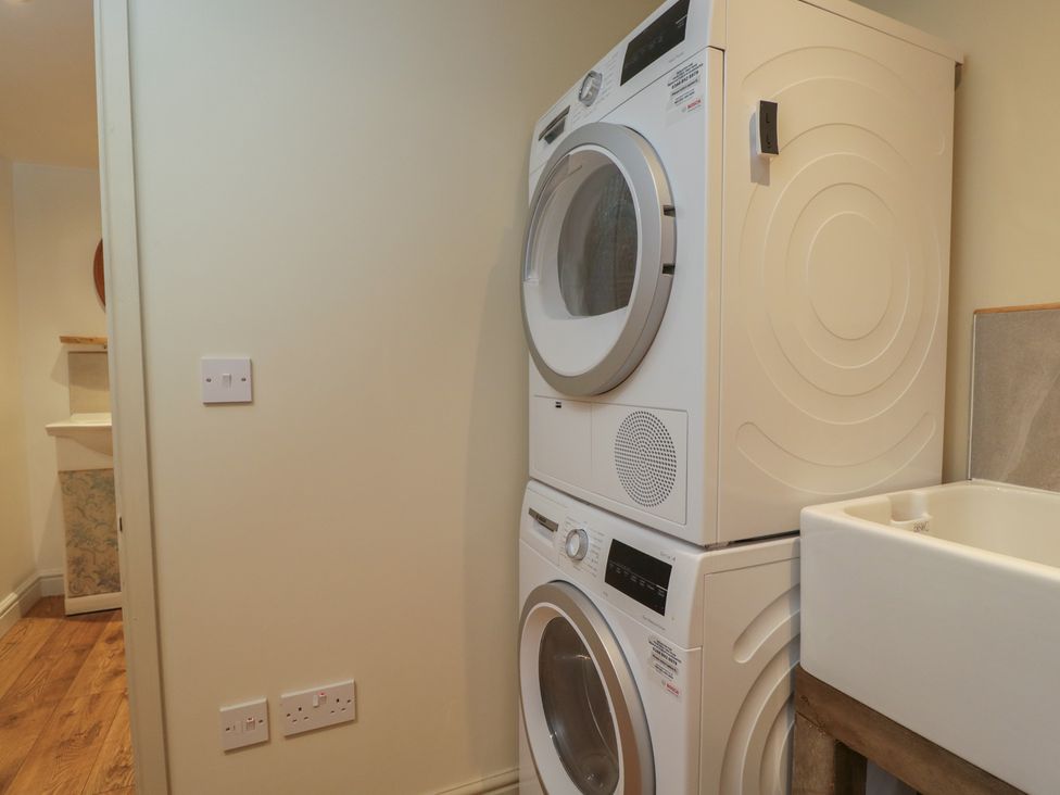 A laundry room with a stacked washing machine and dryer next to a sink at Gardeners Hill Annex