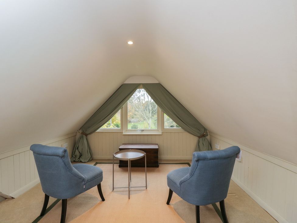 An attic with two armchairs and a small side table at Gardeners Hill Annex