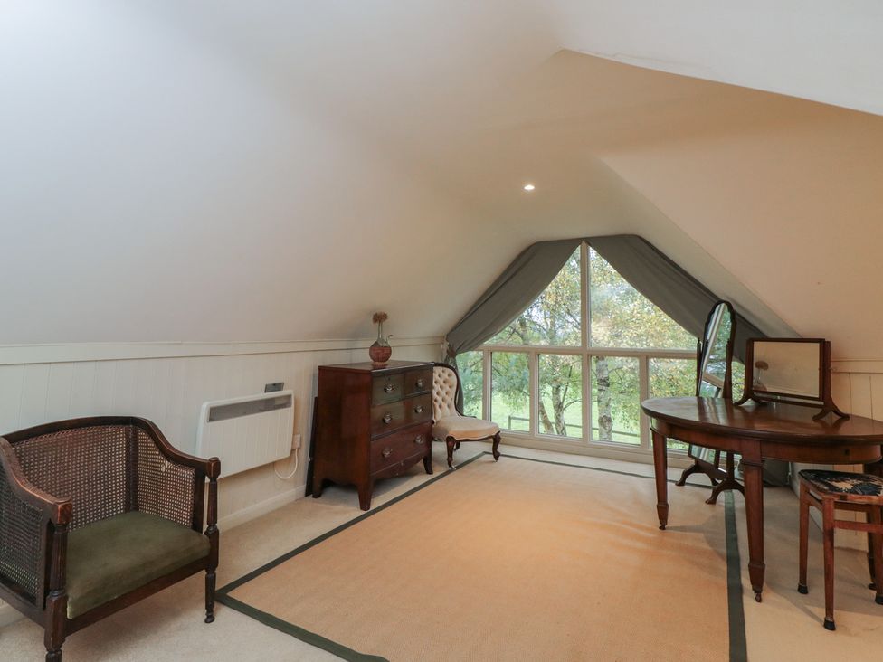 An attic with furniture including a table and armchair at Gardeners Hill Annex