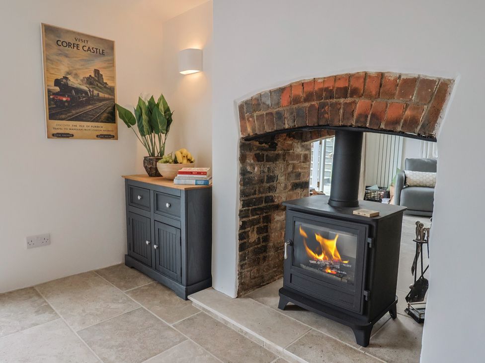 A living room with a wood stove and cabinet at The Old Inn in Winterborne Whitechurch