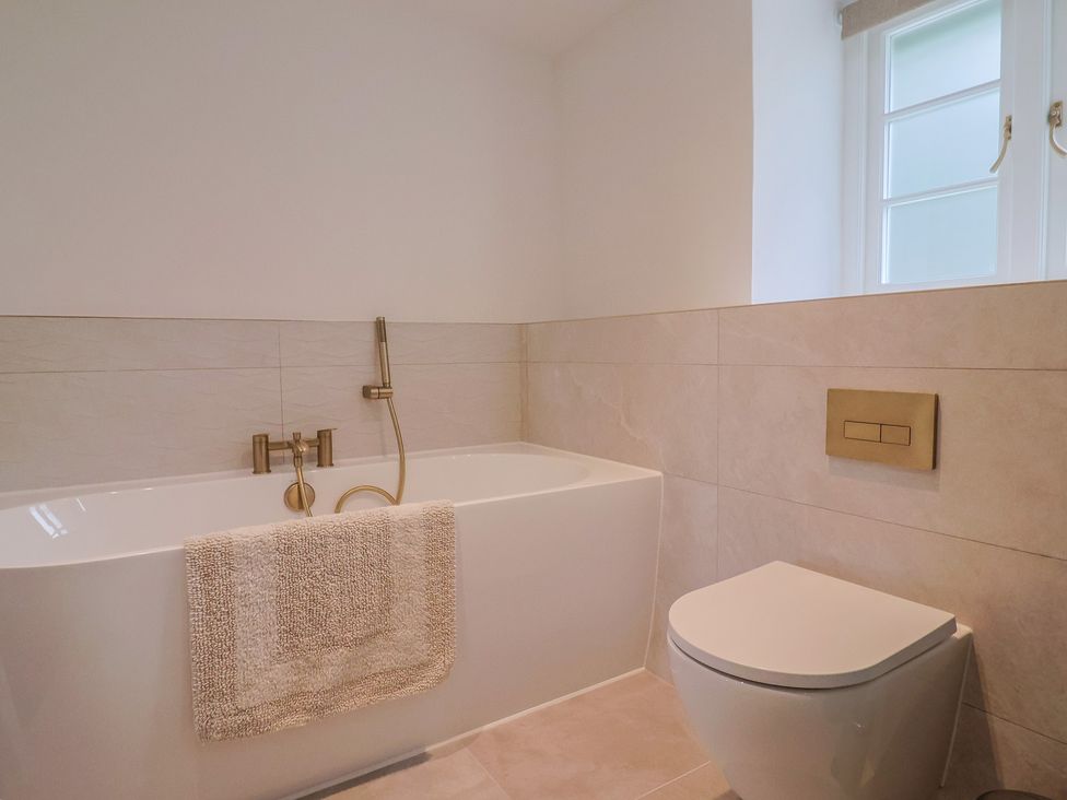A bathroom with a bathtub and a toilet at The Old Inn Winterborne Whitechurch