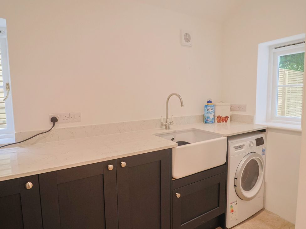 A laundry room with a sink and washing machine at The Old Inn in Winterborne Whitechurch
