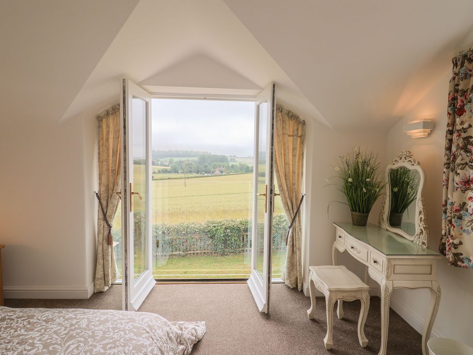 A bedroom with a dressing table and open window at The Old Inn in Winterborne Whitechurch