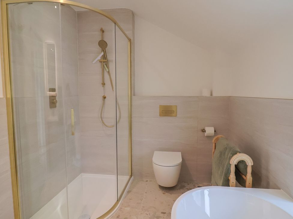A bathroom featuring a shower, toilet, and bathtub at The Old Inn in Winterborne Whitechurch