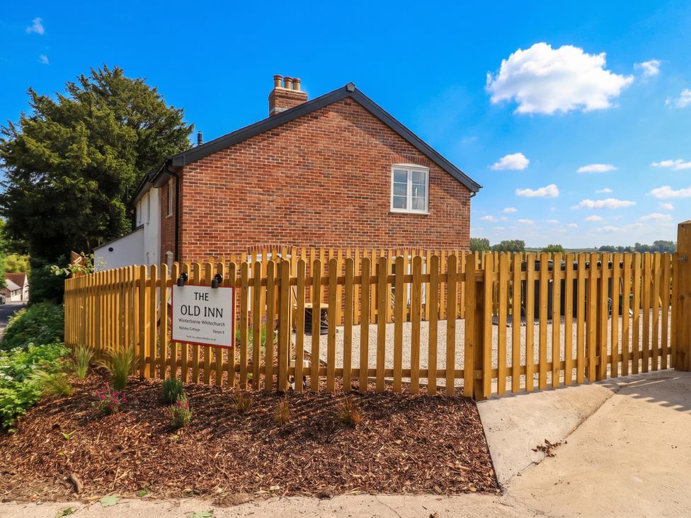 A house with a wooden fence and sign at The Old Inn in Winterborne Whitechurch