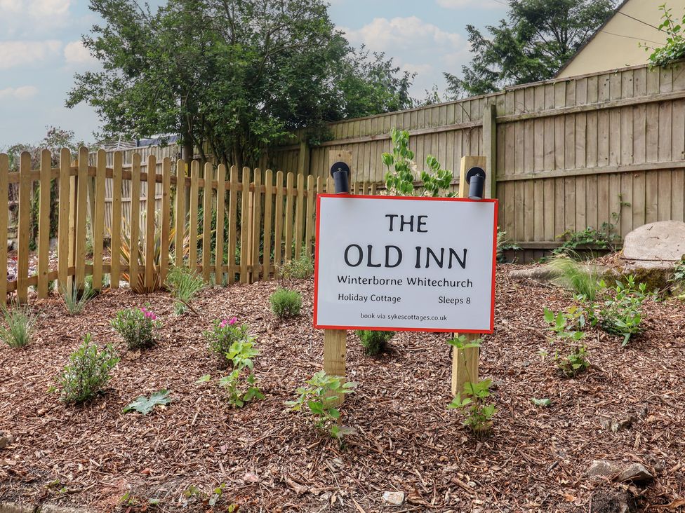 A garden with a sign for The Old Inn in Winterborne Whitechurch