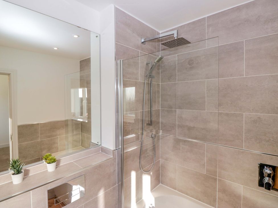 A bathroom featuring a shower, mirror, and sink at 27 Oversands View