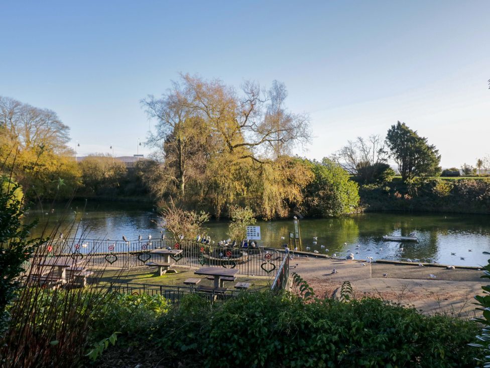 A view of a water body with benches and trees at 27 Oversands View