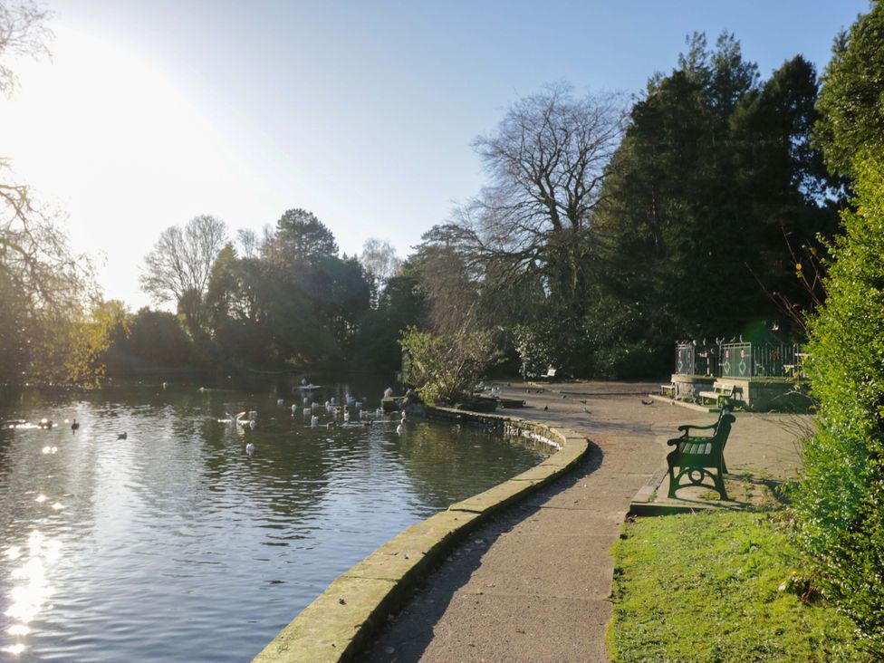 A park with a path alongside a pond and a bench at 27 Oversands View 