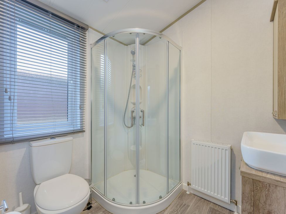 A bathroom with a shower, toilet, and sink at Brayford Lodge (Pet) in Louth