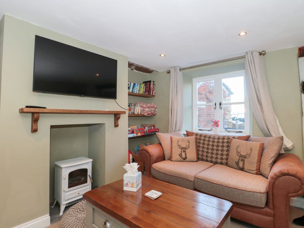 A living room with a television and sofa at The Corner Cottage in Gloucester