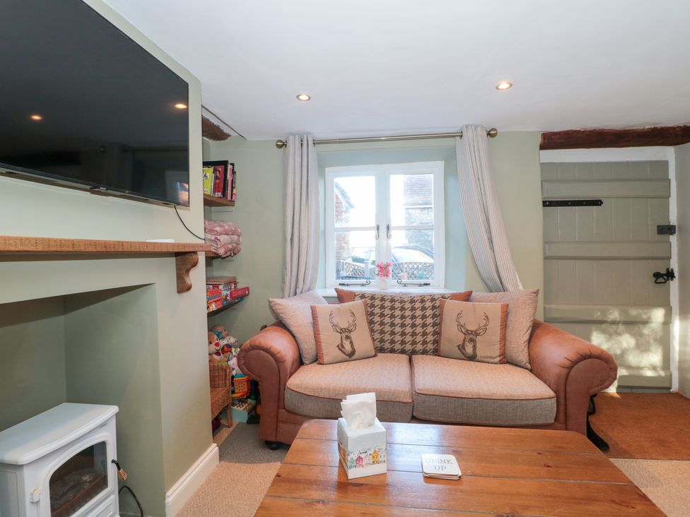 A snug room with a sofa and television at The Corner Cottage in Gloucester