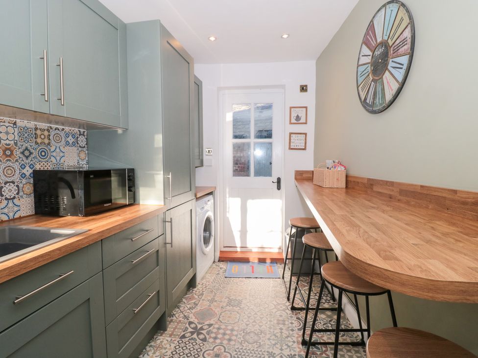 A kitchen with a microwave and washing machine at The Corner Cottage in Gloucester