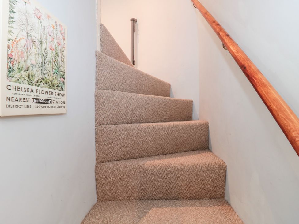Stairs with carpet and handrail at The Corner Cottage in Gloucester