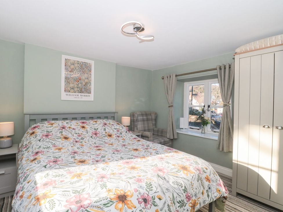 A bedroom with a bed and armchair at The Corner Cottage in Gloucester