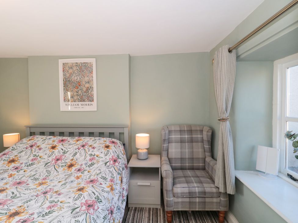 A bedroom with a bed and an armchair at The Corner Cottage in Gloucester