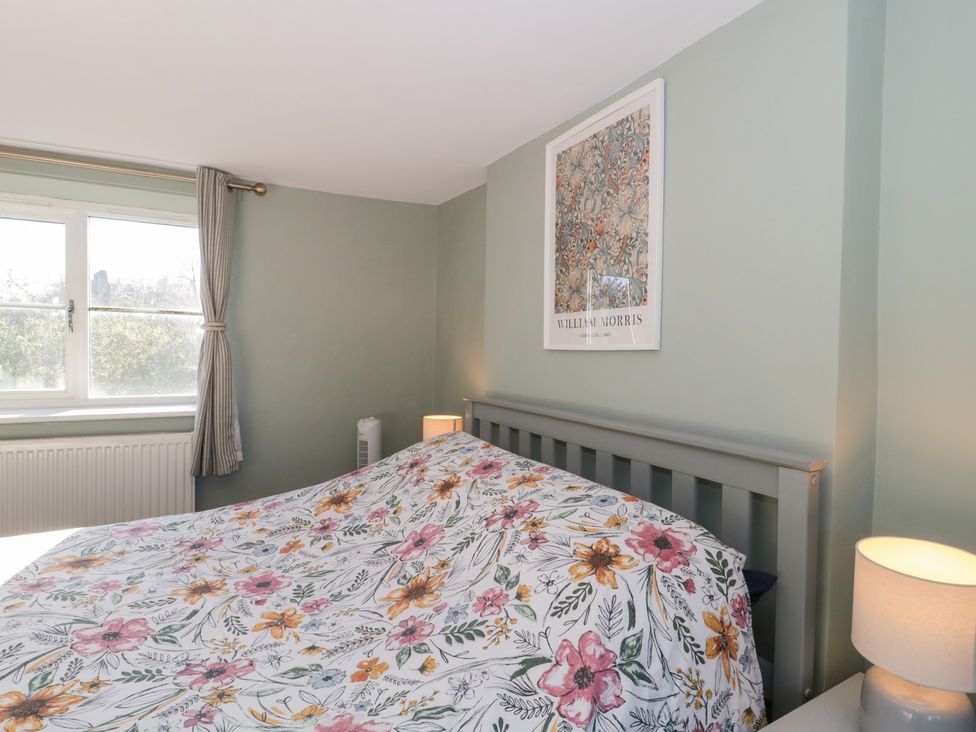A bedroom with a bed and window at The Corner Cottage in Gloucester