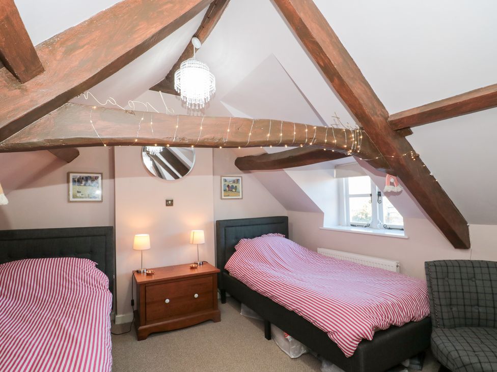 A bedroom with two beds and a mirror at The Corner Cottage in Gloucester