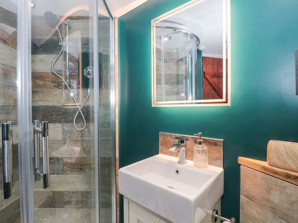 A bathroom featuring a shower, sink, and mirror at The Corner Cottage in Gloucester