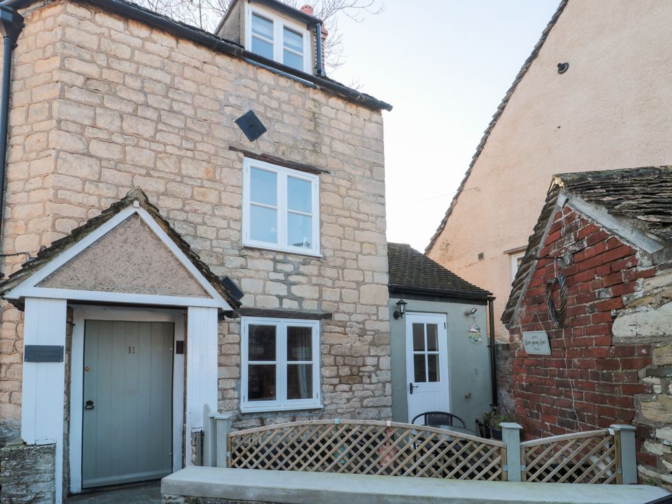 An outdoor view of a cottage with stone walls and windows at The Corner Cottage in Gloucester