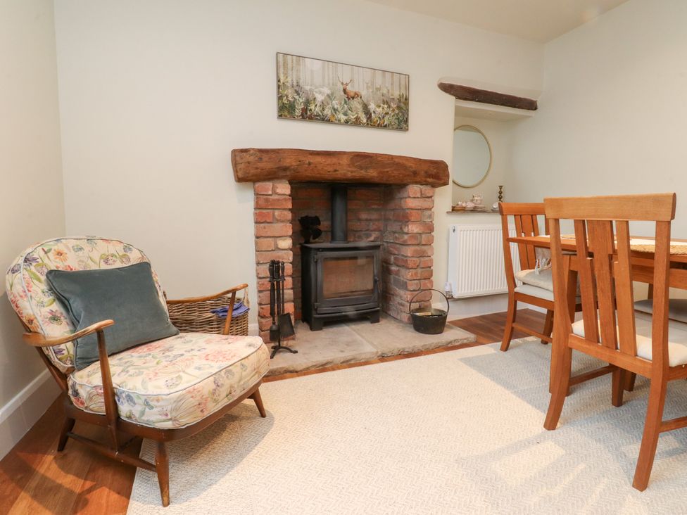 A dining room with a fireplace and an armchair at Cobble Cottage in Clitheroe