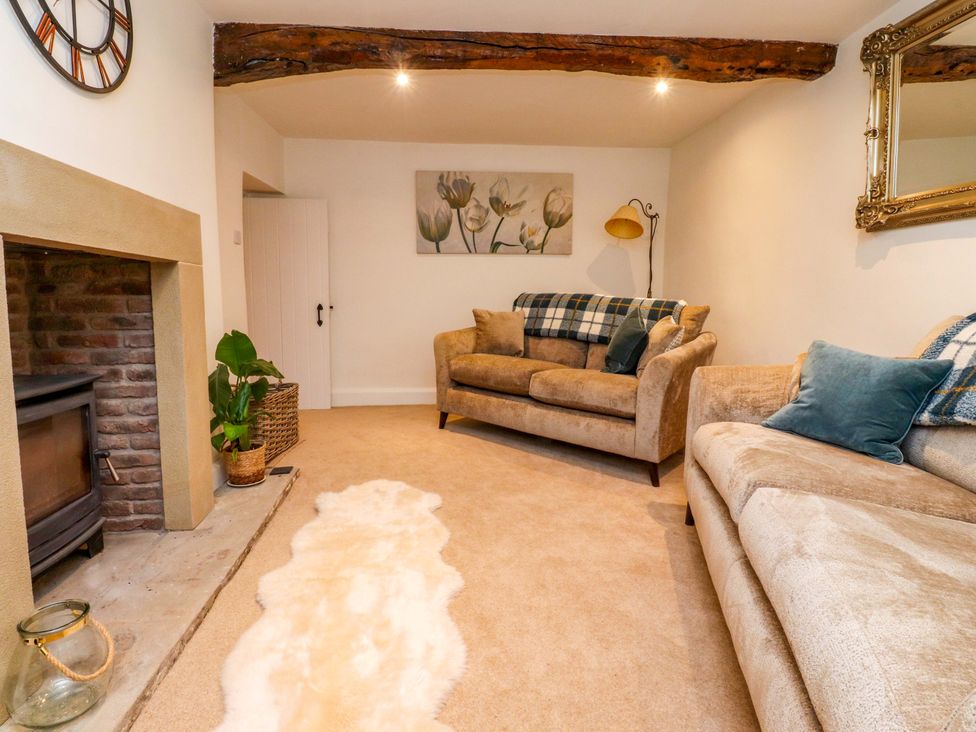 A living room with a sofa, fireplace, and wall art at Cobble Cottage in Gisburn