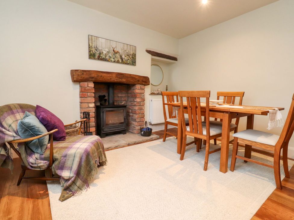 A dining room with a fireplace and an armchair at Cobble Cottage Gisburn
