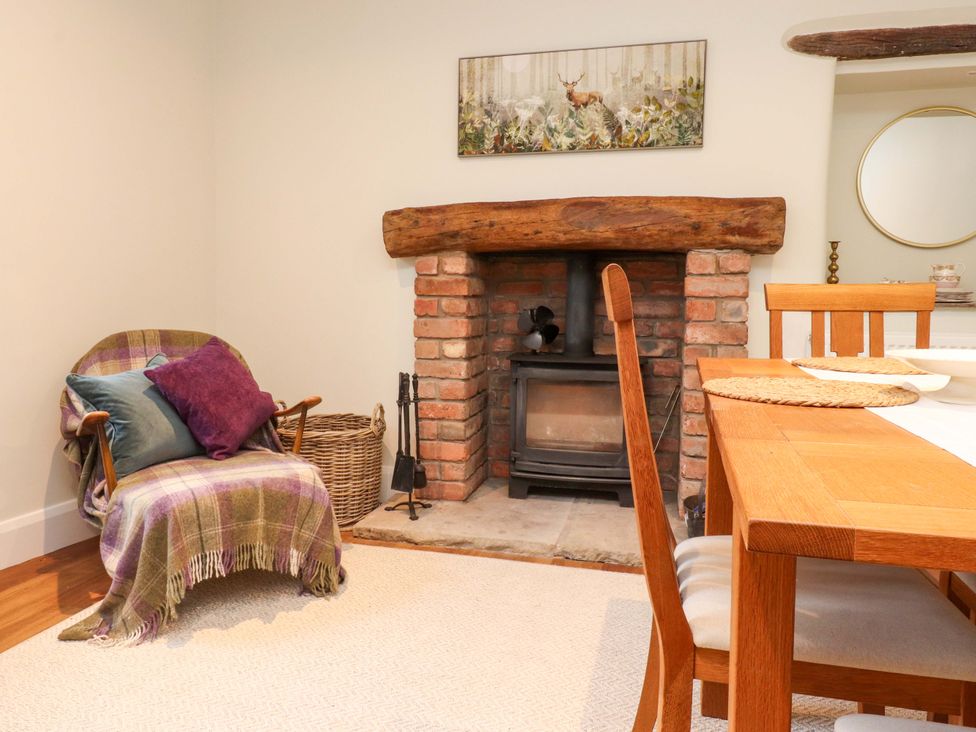A snug with a fireplace and dining table at Cobble Cottage in Gisburn