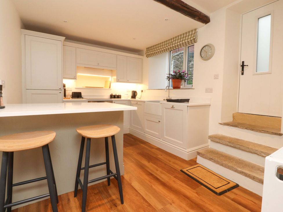 A kitchen with bar stools and a sink at Cobble Cottage in Gisburn