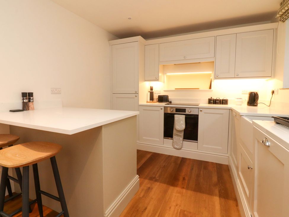 A kitchen with counter and stools at Cobble Cottage Gisburn