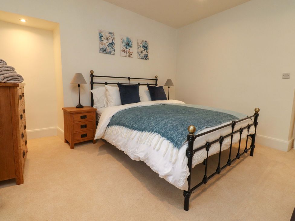 A bedroom with a bed and nightstand at Cobble Cottage in Gisburn