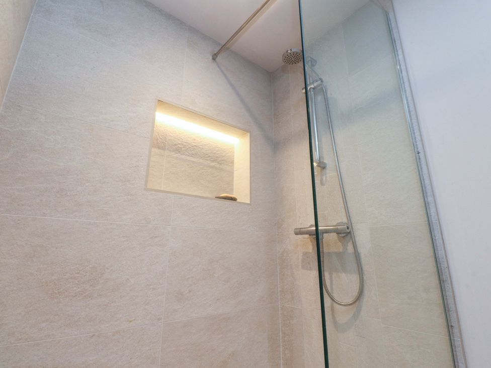 A shower with glass panel and niche at Cobble Cottage in Gisburn