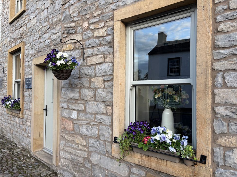 An outdoor view of a stone wall with a door and window at Cobble Cottage in Gisburn
