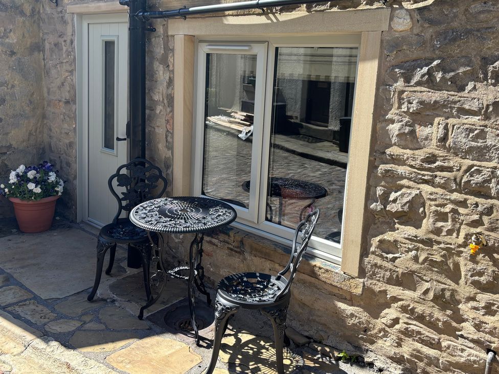 An outdoor seating area with a table and chairs at Cobble Cottage in Gisburn