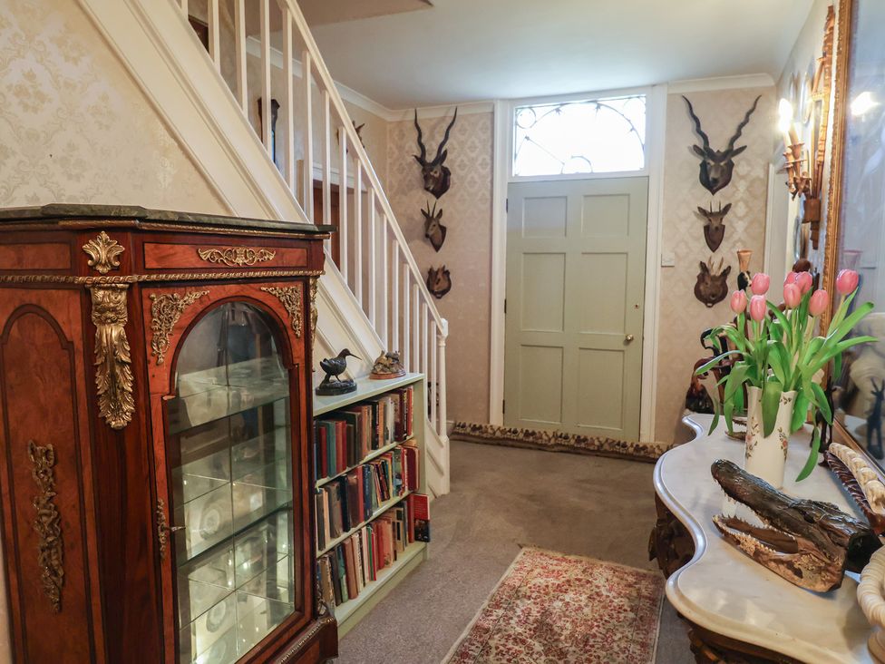 A hallway with a staircase and glass cabinet at Farmhouse in Beccles