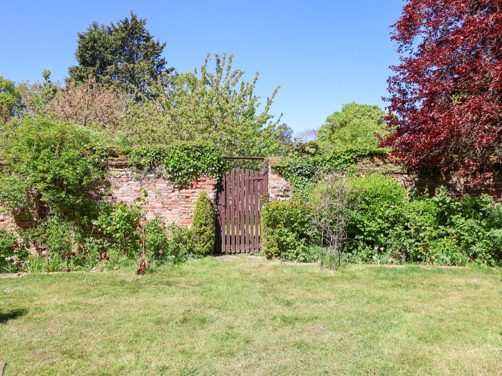 A garden with a wooden gate and greenery at Winston Hall in Beccles