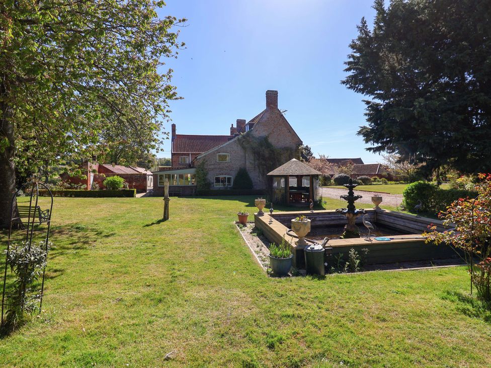A garden with a house and a fountain at Winston Hall in Beccles