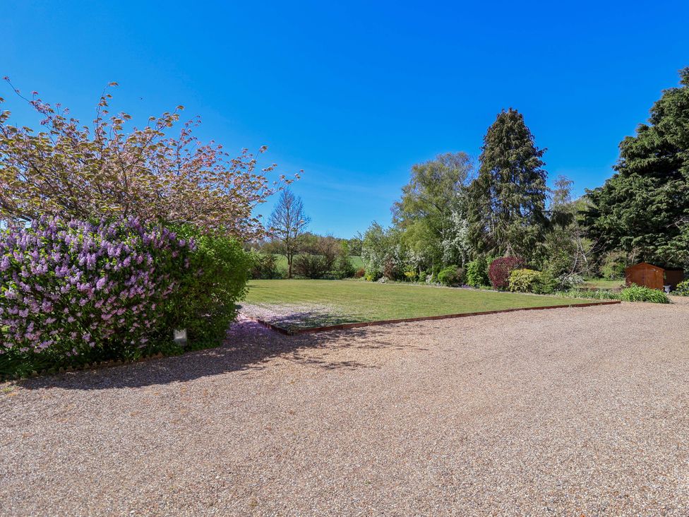 A garden with flowering bushes and a lawn at Winston Hall in Beccles