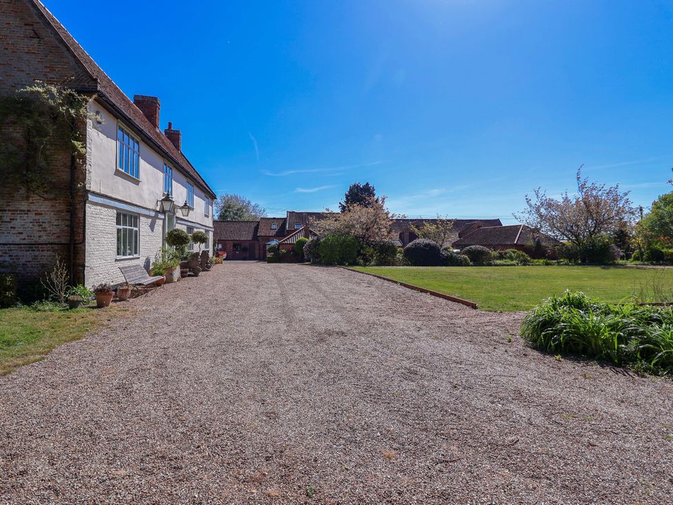 A gravel driveway leading to buildings with greenery at Winston Hall in Beccles